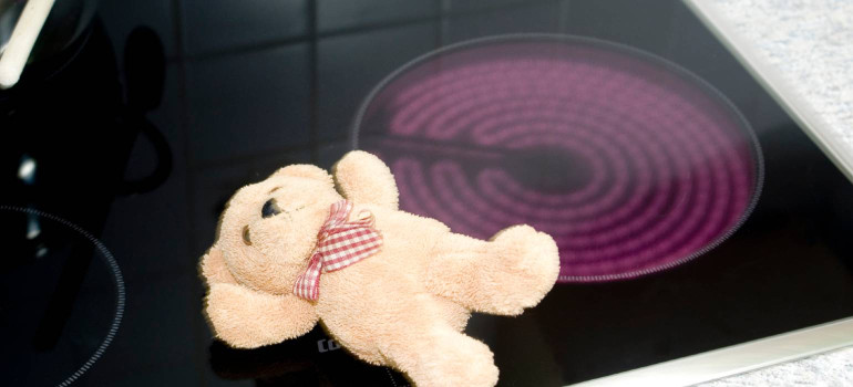 Ein Teddybär liegt auf einer eingeschalteten Herdplatte