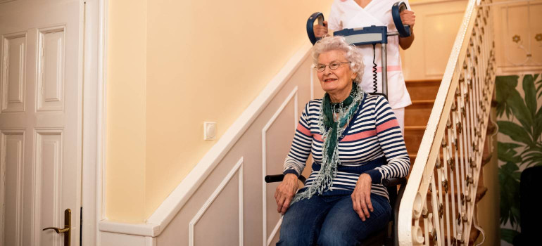 Eine Dame wird mit einem mobilen Treppenlift auf einer Treppe befördert