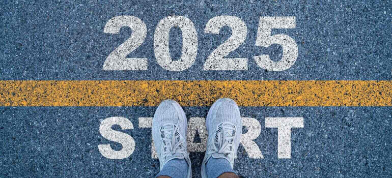 Zwei Füße von oben stehen an einer Startlinie ins Jahr 2025